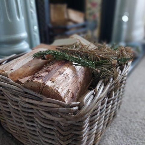 Basket of logs next to a fireplace